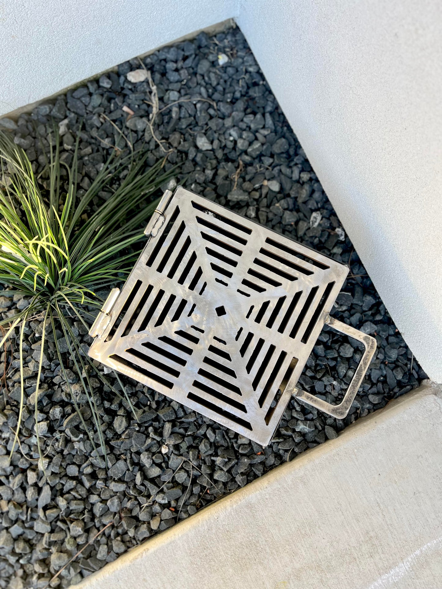 metal rocket stove on a forest floor with trees in the background camping and high heat cooking fireplace with grill top attachment to cook on top