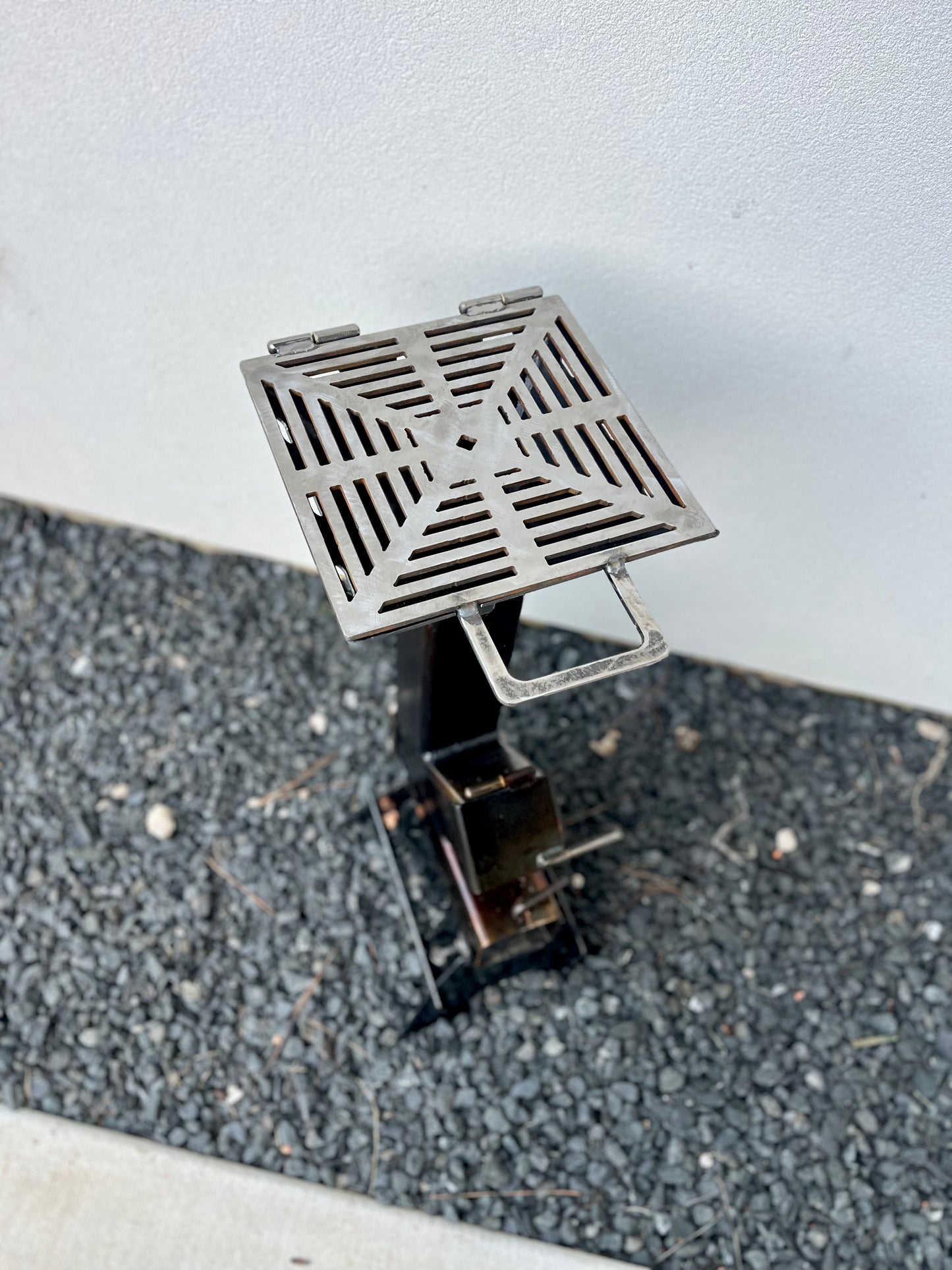 Metal grill top for rocket stove grey cooktop metal rocket stove on a forest floor with trees in the background camping and high heat cooking fireplace with grill top attachment to cook on top