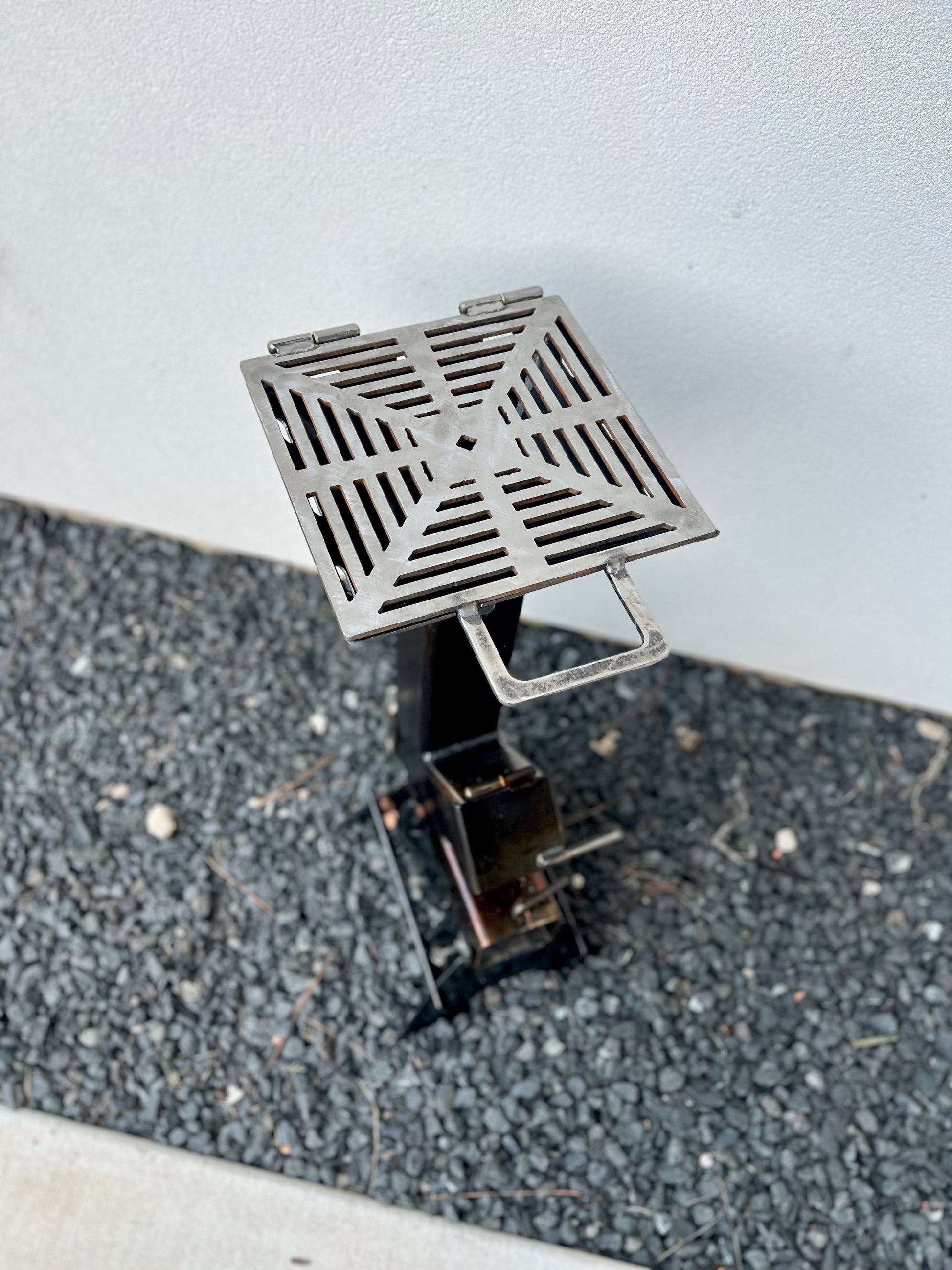 Metal grill top for rocket stove grey cooktop metal rocket stove on a forest floor with trees in the background camping and high heat cooking fireplace with grill top attachment to cook on top